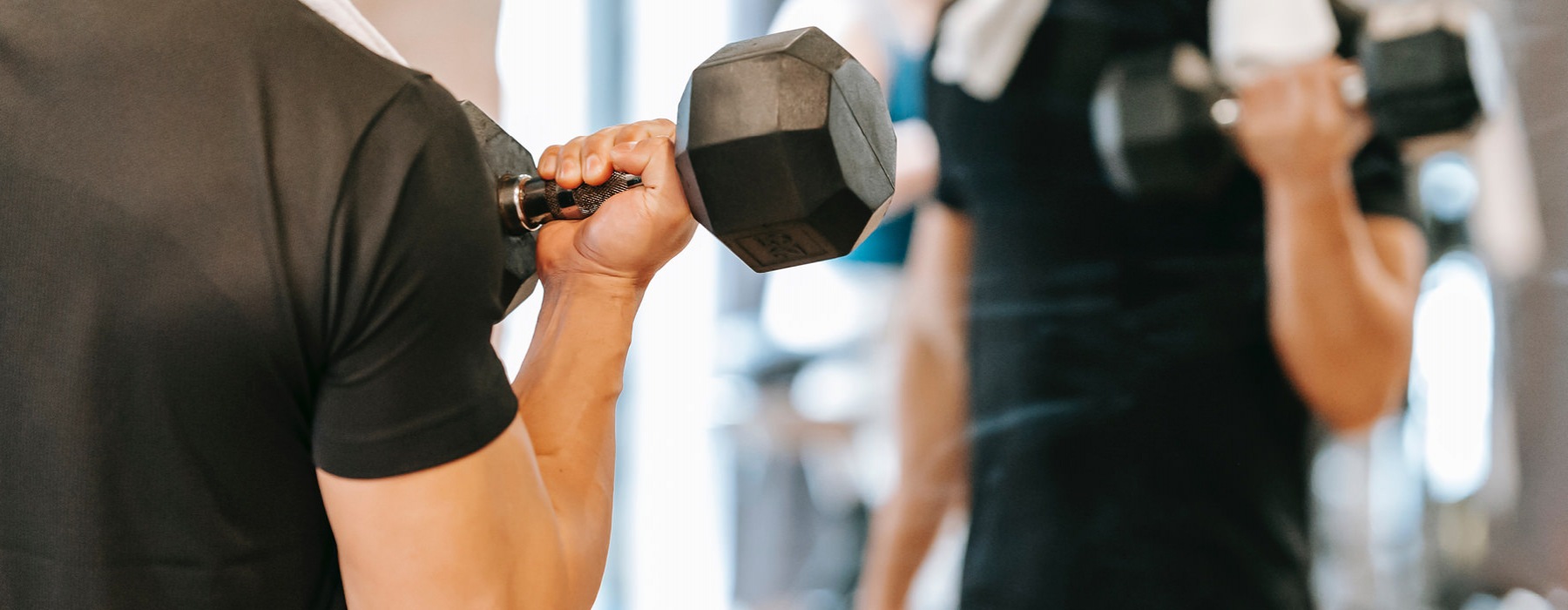 man exercises with dumbell in front of mirror