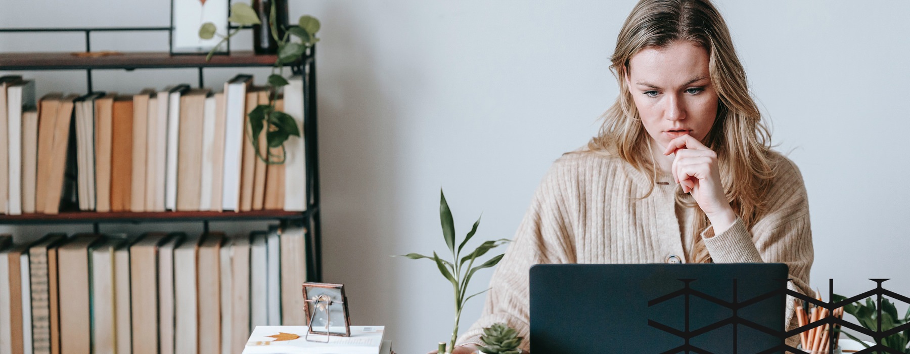 woman sits at her desk and works on laptop